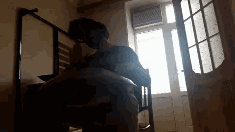 a man is sitting in a chair in front of a window