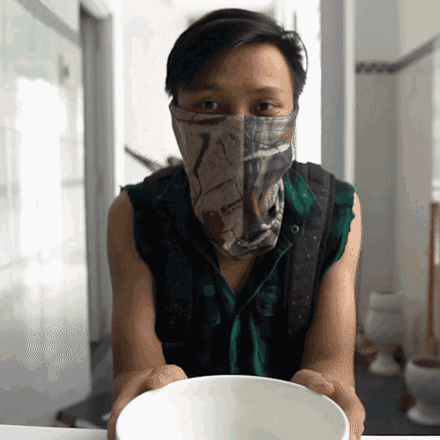 a man wearing a face mask holds a bowl