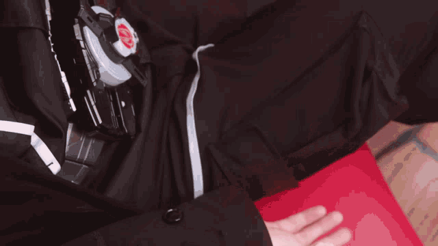 a person 's hand is reaching out in front of a black shirt with a red letter k on it