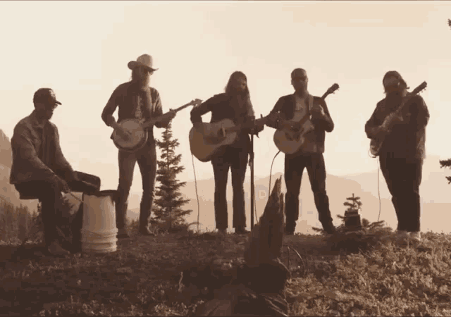 a group of men playing guitars and banjos in front of a mountain