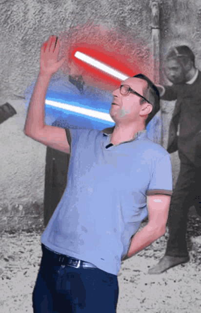 a man in a blue shirt is holding a blue and red light saber