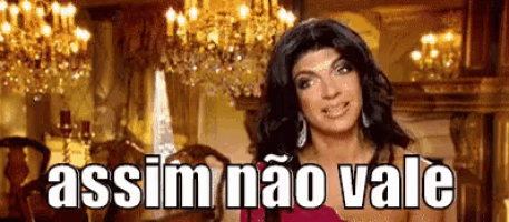 a woman in a red dress is standing in a room with chandeliers and says assim não vale .