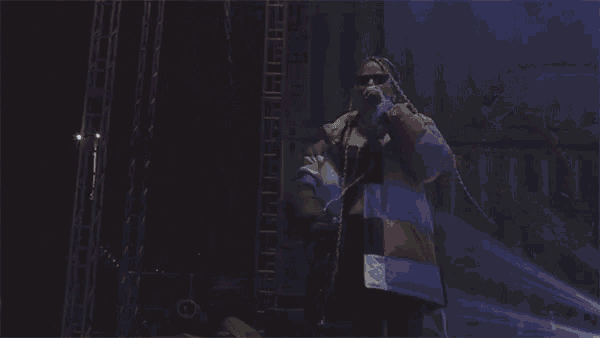 a man with dreadlocks is singing into a microphone on stage