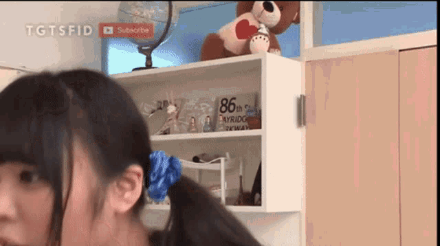 a girl is standing in front of a shelf that says 86th skybridge