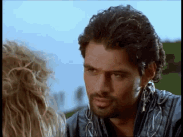 a man with a beard and earrings is looking at a woman