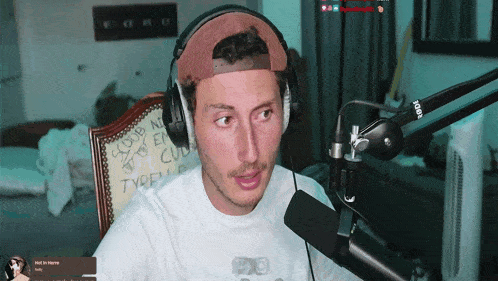 a man wearing headphones sits in front of a rode brand microphone