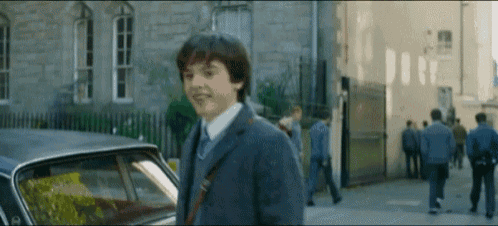 a young man in a suit and tie is walking down the street