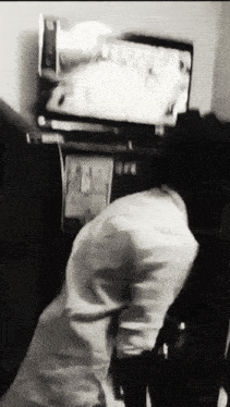 a black and white photo of a person in front of a television