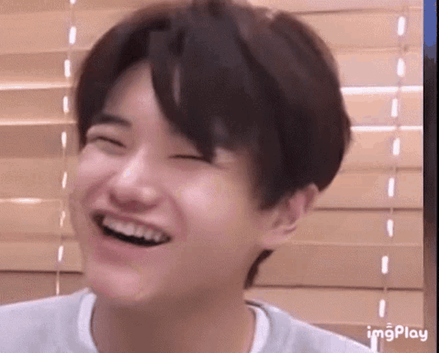 a young man is laughing with his eyes closed and his mouth open .
