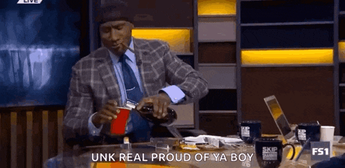 a man in a suit is pouring a drink into a red cup