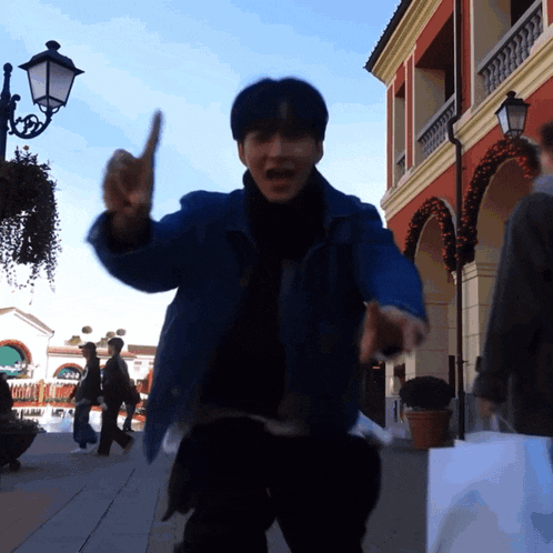 a man in a blue jacket is pointing upwards