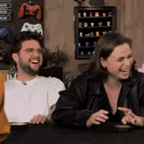 a man and woman are sitting at a table laughing .