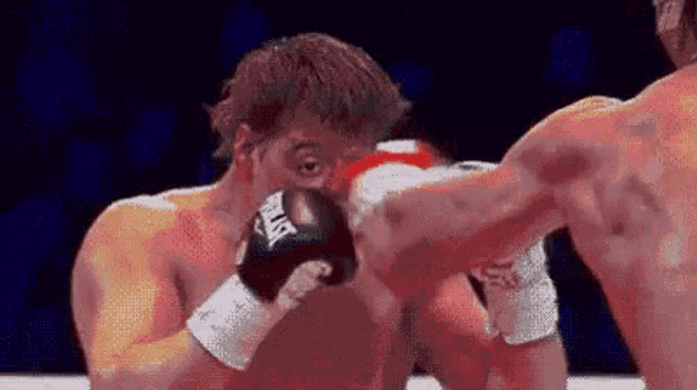 two men are boxing in a ring and one of the men is wearing everlast gloves .