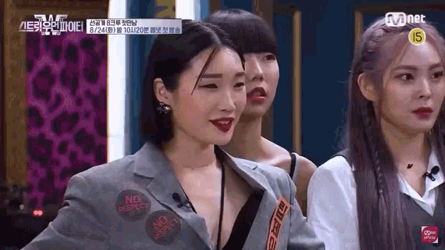a group of women are standing next to each other on a stage and one of them is wearing a jacket with stickers on it .