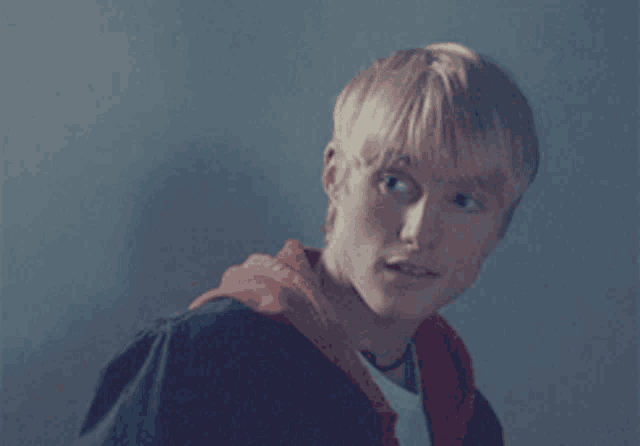 a young man with blonde hair wearing a red hoodie