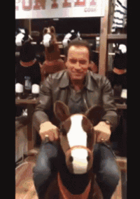 a man is sitting on a stuffed horse in front of a sign that says fun