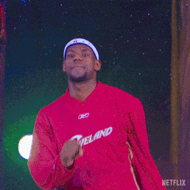 a man wearing a red cleveland jersey stands in front of a blue background