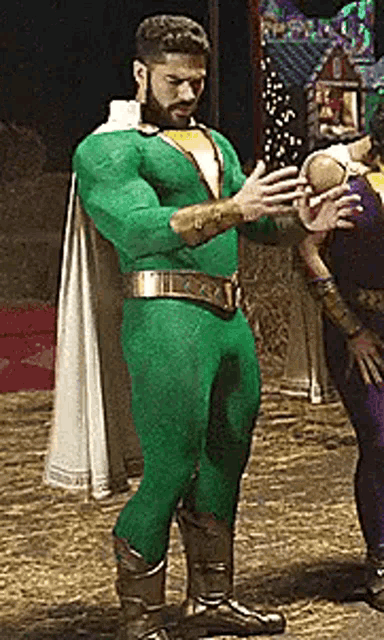 a man in a green superhero costume is standing next to a woman in a purple costume .