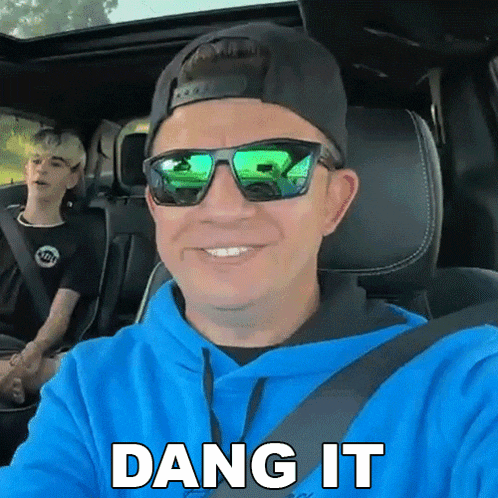 a man wearing sunglasses and a blue hoodie says dang it while sitting in a car