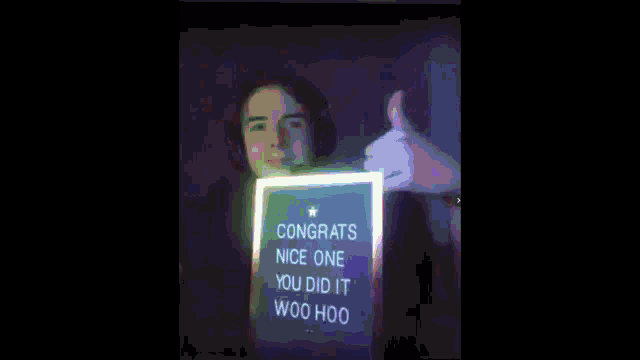 a young man is holding a sign that says congrats nice one you did it woohoo