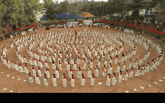 a large group of people are dancing in a circle in front of a large crowd