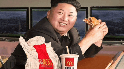 a man in a suit and tie is eating a sandwich and drinking a mcdonald 's drink .