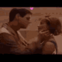 a man and woman are kissing with a pink heart in the background .