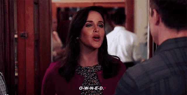 a woman is talking to a man in a room while wearing a purple sweater .