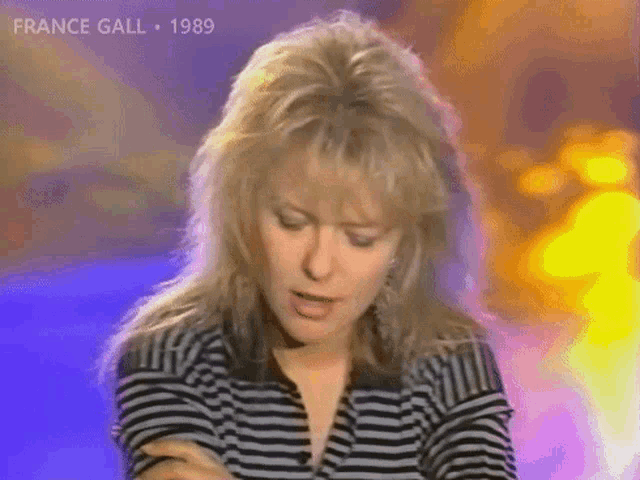 a woman with blonde hair is wearing a striped shirt and the year 1989