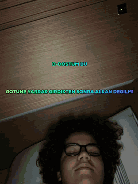 a man with glasses is laying on a bed with the words d-dostum bu written above him
