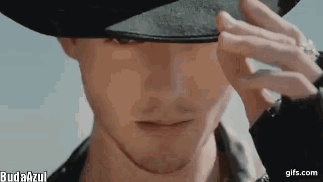a close up of a man wearing a cowboy hat covering his eye .