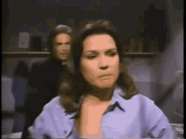 a woman in a purple shirt is sitting in front of a man in a black suit .