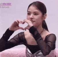 the woman is making a heart shape with her hands .