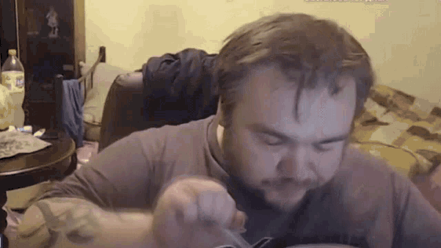 a man in a gray shirt is eating something