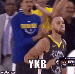 a basketball player is standing in front of a crowd and ykb is written on the screen behind him .