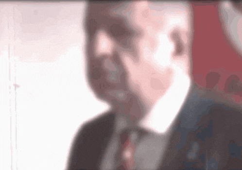 a blurry picture of a man in a suit and tie with a red background