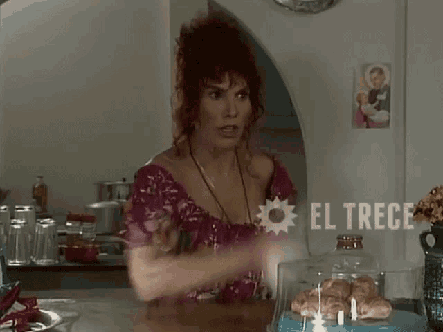 a woman sitting at a counter with a sign that says el trece on it