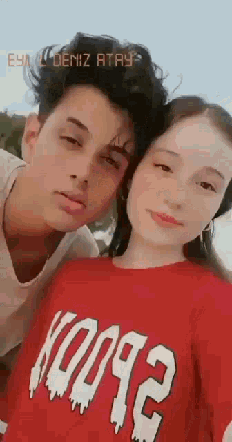 a boy and a girl are posing for a picture and the girl is wearing a red shirt that says ko092 on it