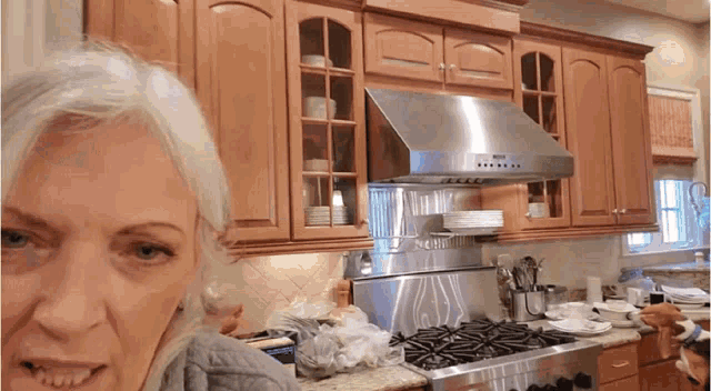a woman in a kitchen with stainless steel appliances and a stove top oven