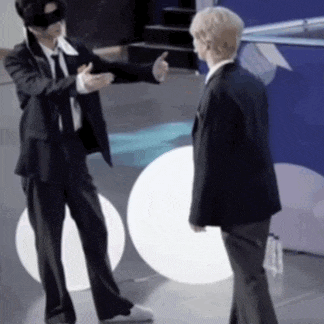 two men in suits are standing next to each other talking .