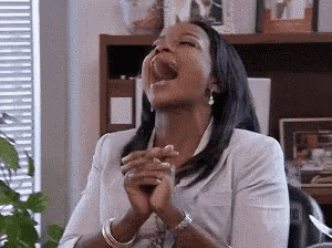 a woman is laughing with her mouth open and her hands folded .