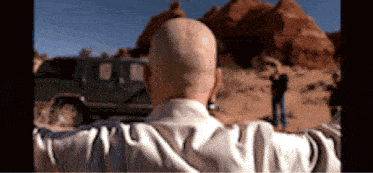 a man with a bald head stands in front of a jeep