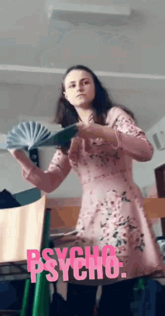 a girl in a pink floral dress is holding a fan with psycho written in pink