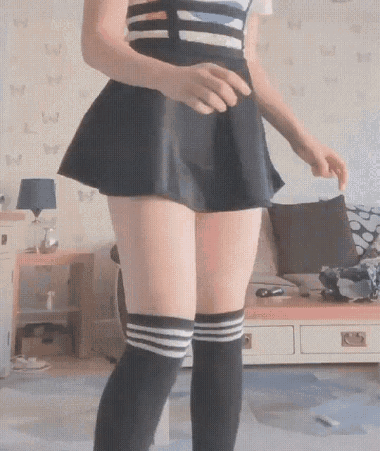 a woman wearing knee high socks and a skirt is standing in a living room