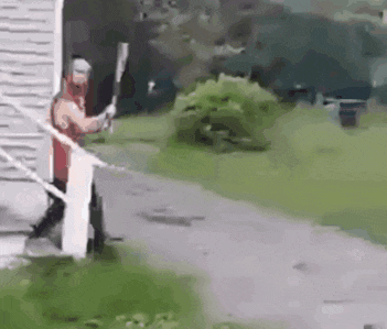 a man is standing on a porch holding a bat .