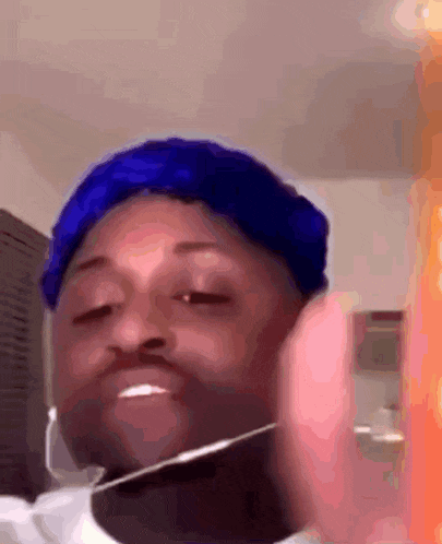 a man wearing a blue hat and headphones is making a funny face .