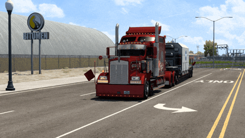 a red semi truck is parked on the side of the road in front of a bitumen sign