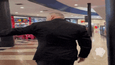 a man in a suit is walking in a mall