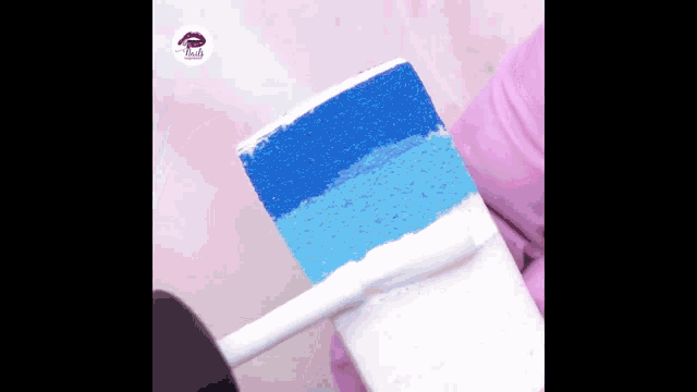 a person is holding a piece of cake with blue and white frosting .