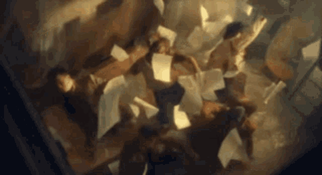 a group of people are laying on the floor with papers flying around them .